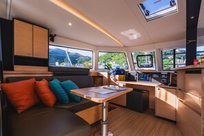 Ein kompakter Innenraum mit einer Couch, einem Tisch, einer Bedienkonsole und Blick ins Freie.
