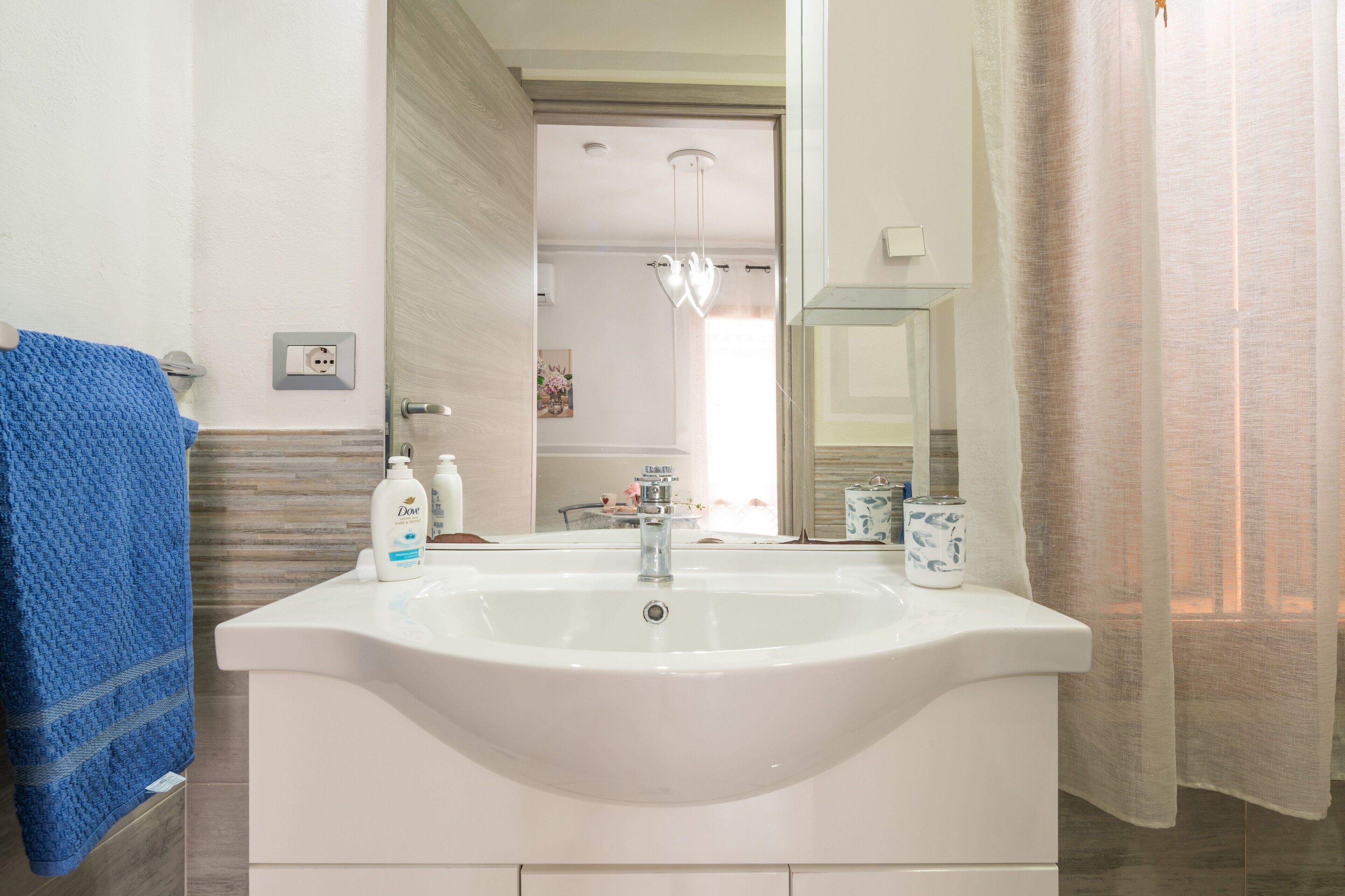 Un baño con un lavamanos blanco, una toalla azul y artículos de aseo.