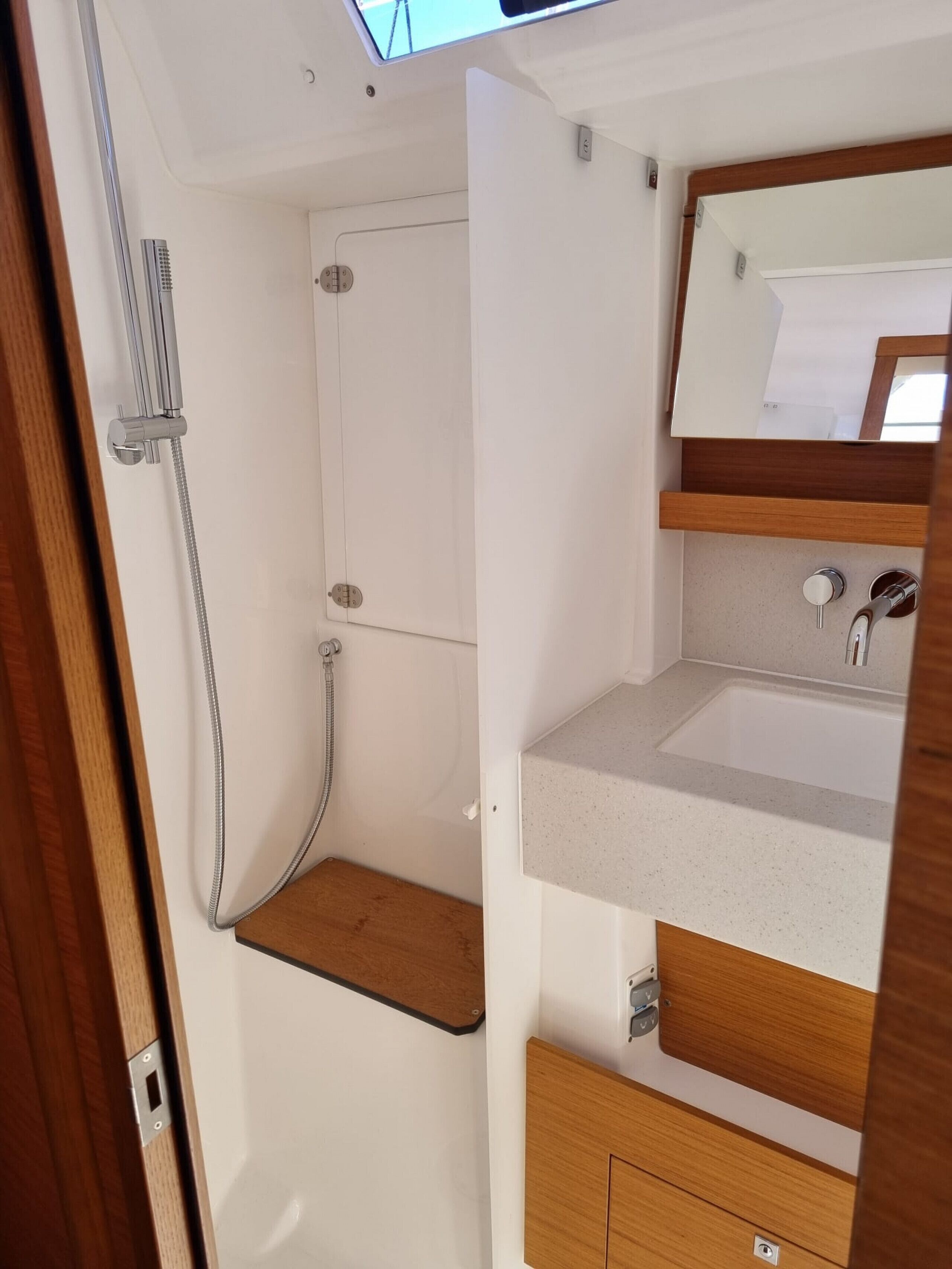 A compact bathroom with a shower, a sink, and a mirror.