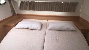 Un lit double avec une tête de lit en bois, deux oreillers et une fenêtre avec des rideaux.