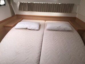Ein Doppelbett mit hölzernem Kopfteil, zwei Kissen und einem Vorhangfenster.