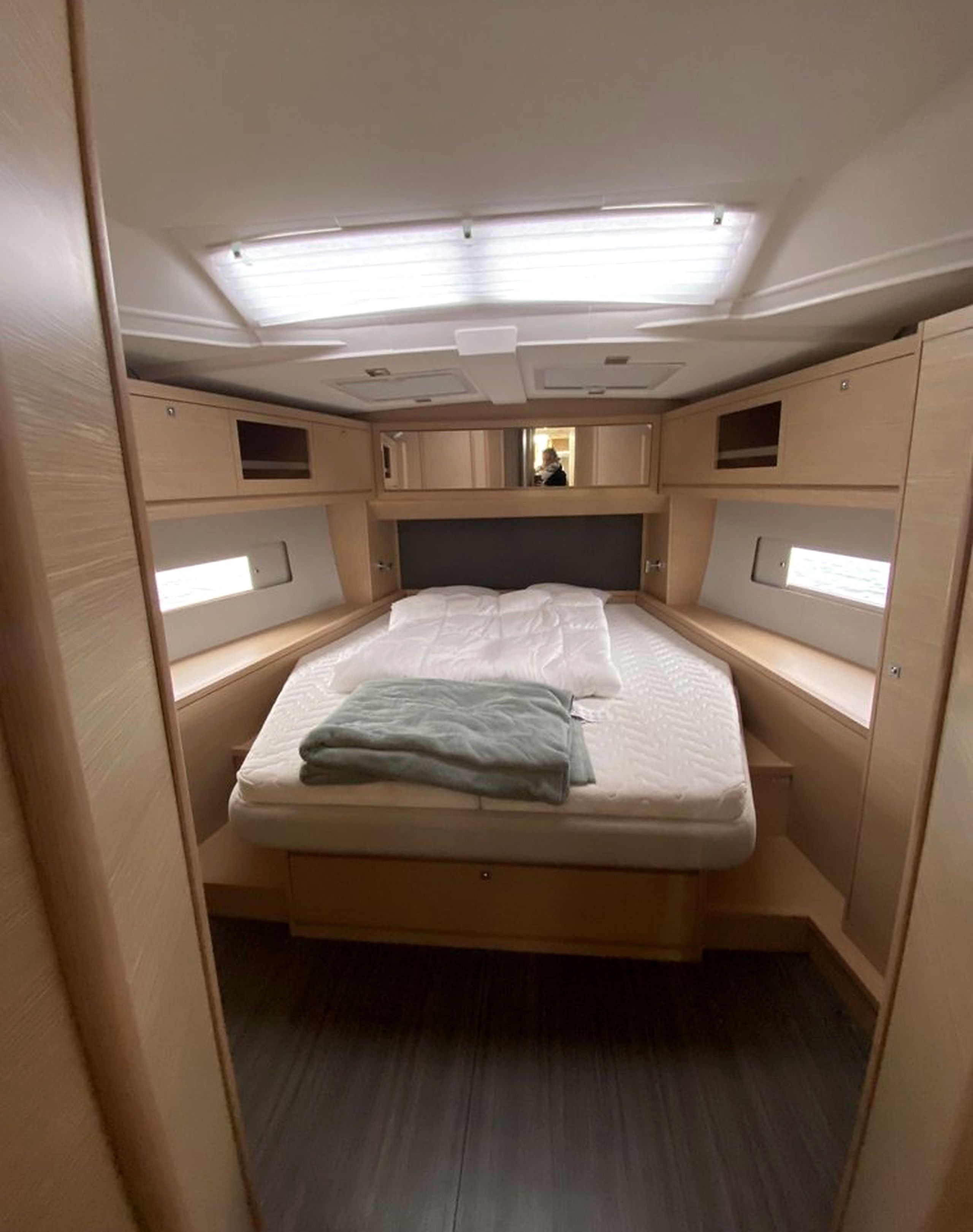 Une chambre à coucher compacte et bien éclairée, avec un lit simple, des placards intégrés et une lucarne au plafond.