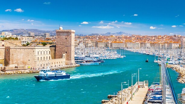 Un port avec des bateaux, un bâtiment historique et une vue sur la ville en arrière-plan.