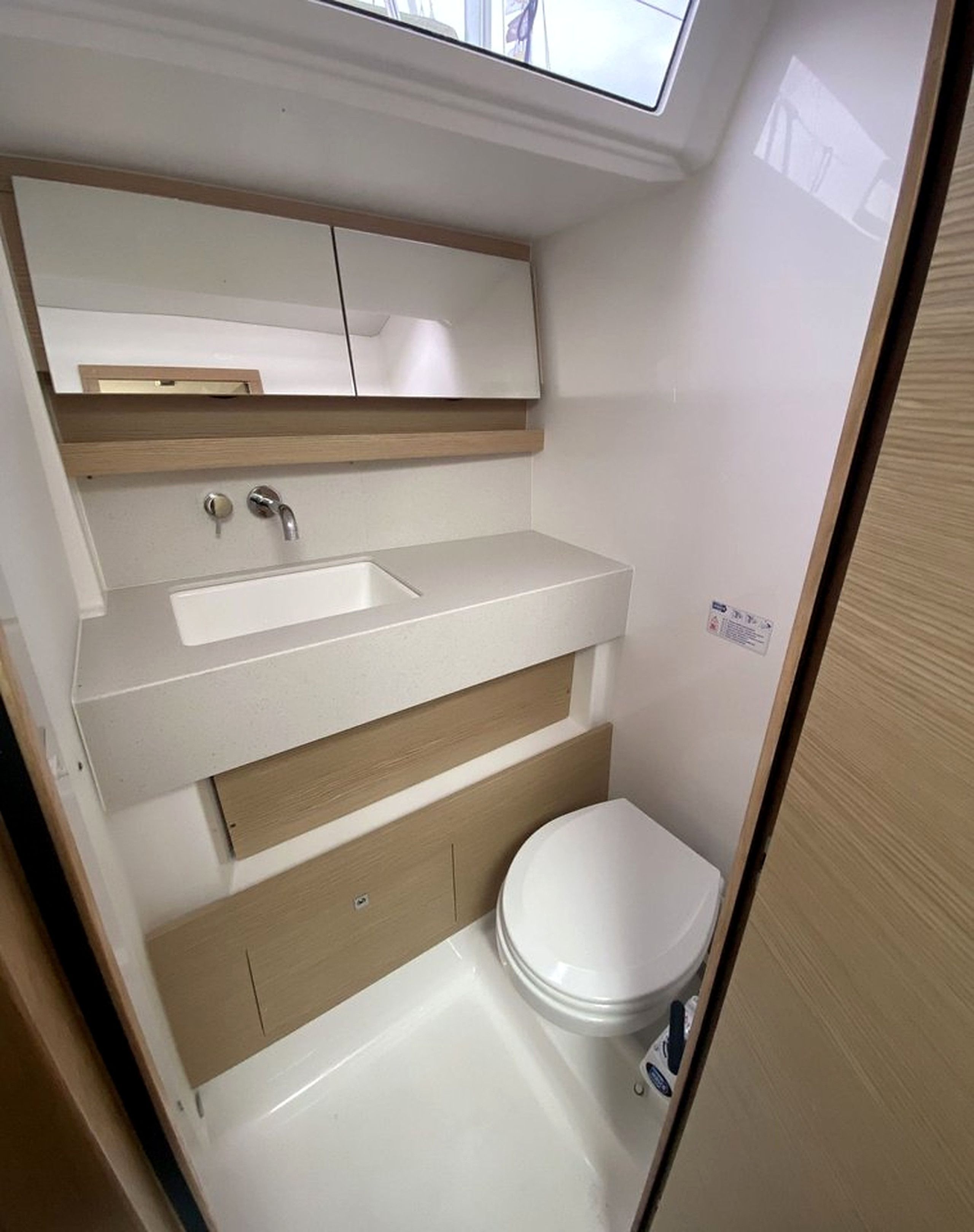 Een kleine badkamer met een ingebouwd wastafel, spiegel en toilet.
