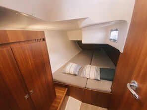 Un intérieur réduit en espace, comprenant un lit, une petite fenêtre et une porte.