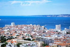 A coastal cityscape with dense urban buildings, a clear blue sea, and distant hills. - Sun-Kissed Sailing Adventure to Viejo Puerto (Marseilles)