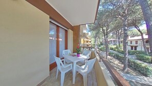 Ein Balkon mit Tisch und Stühlen, einem Blumentopf und Blick auf eine Wohngegend mit Bäumen und Gebäuden.