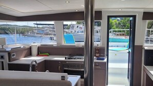 A boat's interior with a kitchen area, a dining space, and a view of the marina. - Caribbean Dream: Sun-soaked Sailing Adventure from Tortola, Islas Vírgenes Británicas (Road Town)