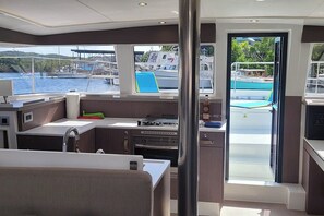 Das Schiffsinnenleben mit Küchenbereich, Essbereich und Blick auf den Yachthafen.