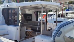 A yacht with an open deck, a seating area, and a small table. - Caribbean Dream: Sun-soaked Sailing Adventure from Tortola, Islas Vírgenes Británicas (Road Town)