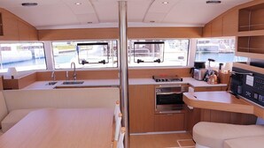 Una cocina compacta con pileta, estufa y horno, muebles de madera y ventana con vista a barcos.