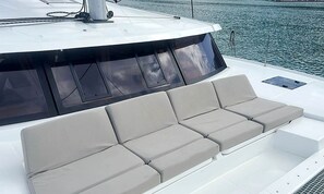 A boat's deck with a row of cushioned seating and a covered area. - Sun-Kissed Sailing Adventure in Isla de Mahe, Seychelles (Victoria)