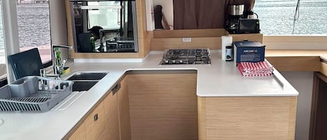 Een compacte keuken met een spoelbak, fornuis en uitzicht op het water.