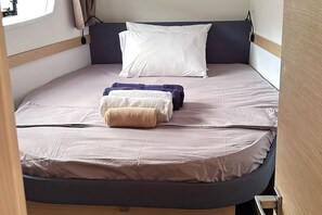 A compact bed with a headboard, a pillow, and rolled towels. - Sun-Kissed Sailing Adventure in Isla de Mahe, Seychelles (Victoria)