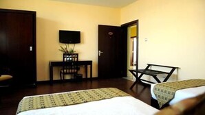 A hotel room with two beds, a desk, a chair, a television, and a door. - Destiny Addis Hotel (Addis Ababa)