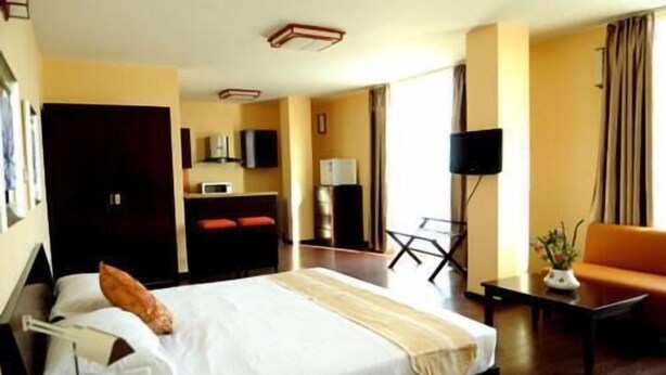 A hotel room with a bed, a desk, a chair, a sofa, a TV, and a door. - Destiny Addis Hotel (Addis Ababa)