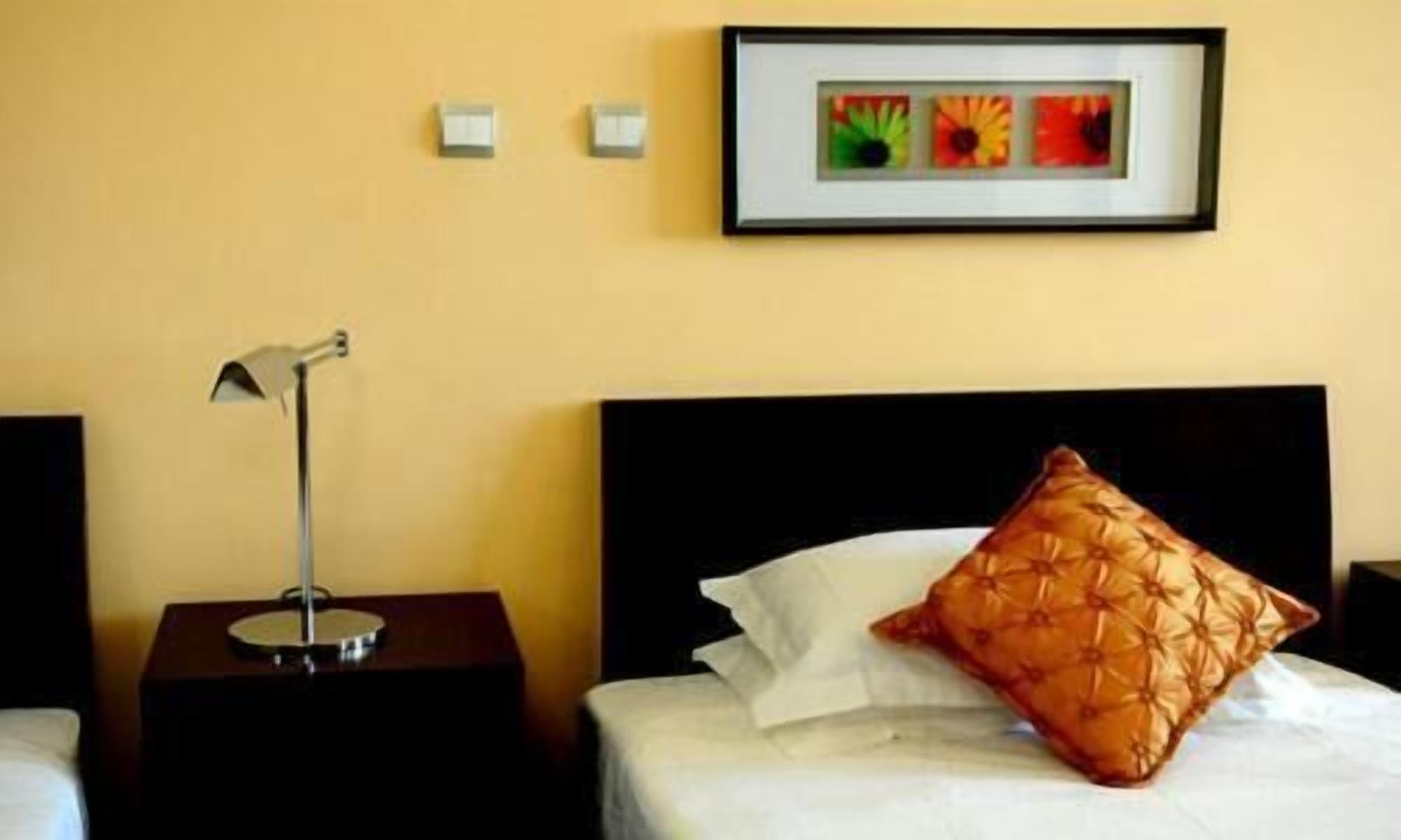 Una camera d'albergo con un letto, un comodino con una lampada e un quadro appeso al muro.