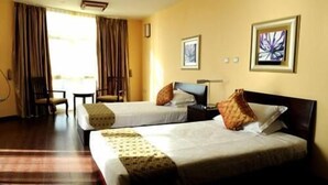A hotel room with two beds, a desk, a chair, and a window with curtains. - Destiny Addis Hotel (Addis Ababa)