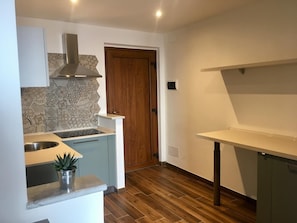 A kitchen with a built-in stove, a sink, and a wooden door.