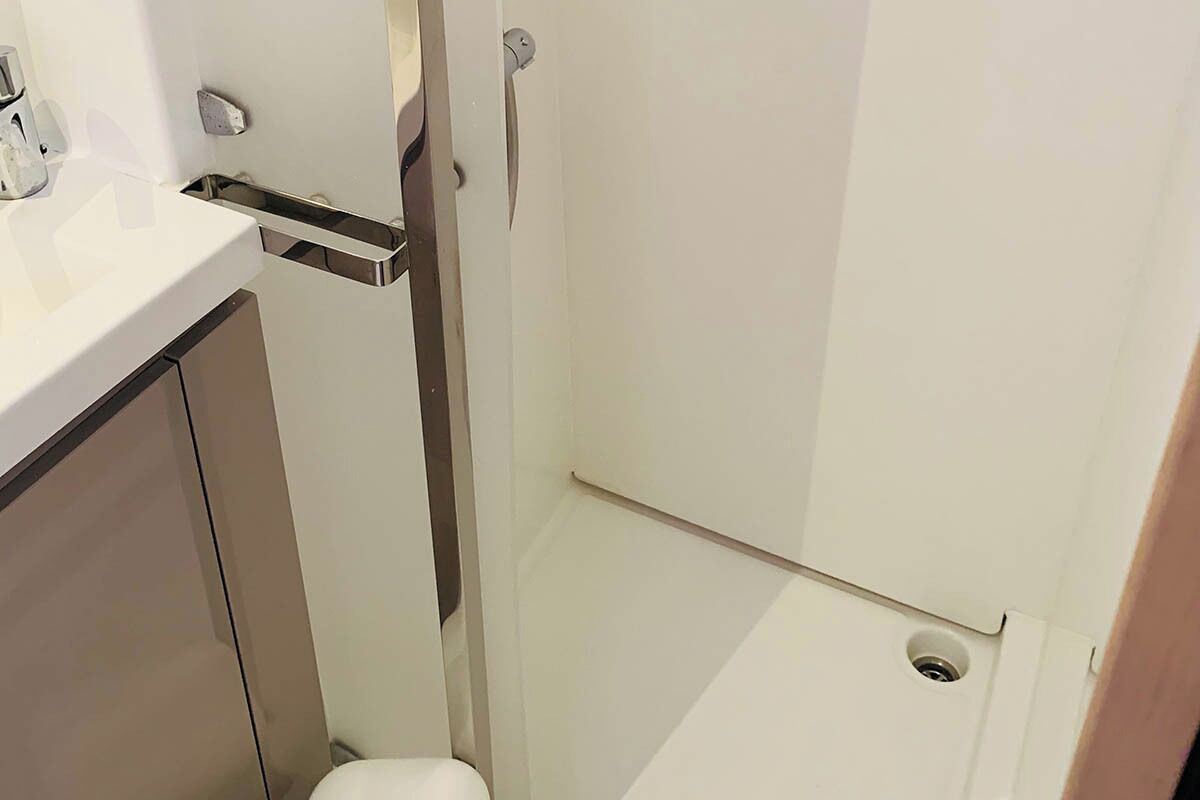 Et badeværelse med en hvid vask, toilet og bruseniche.