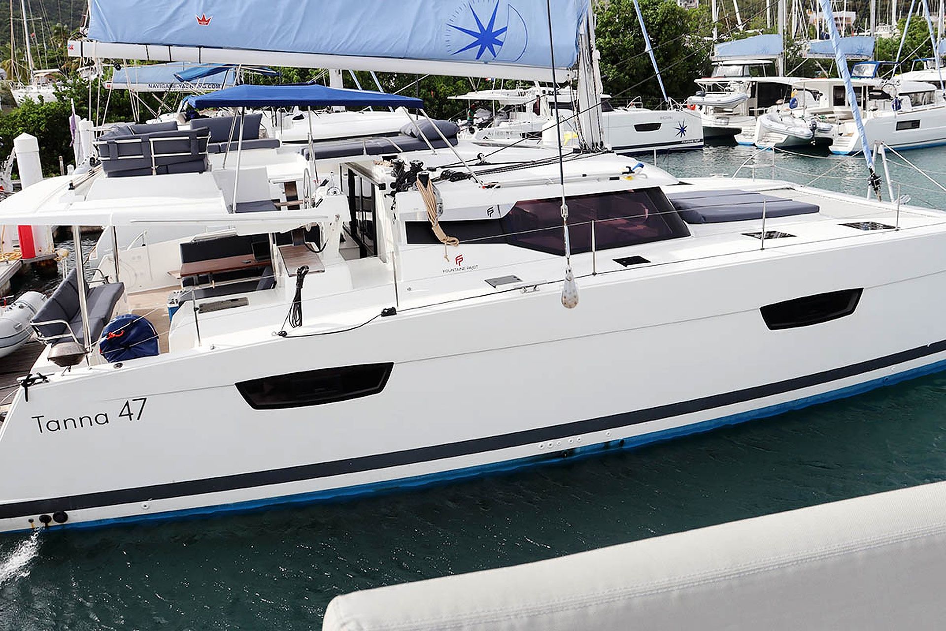 Un yate blanco llamado 'Tanna 47' atracado en un puerto deportivo con varios otros barcos.