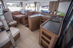 A compact kitchen with a sink, stove, and seating area. - Sun-Kissed Sailing Adventure in the Saronic Islands (Elliniko)