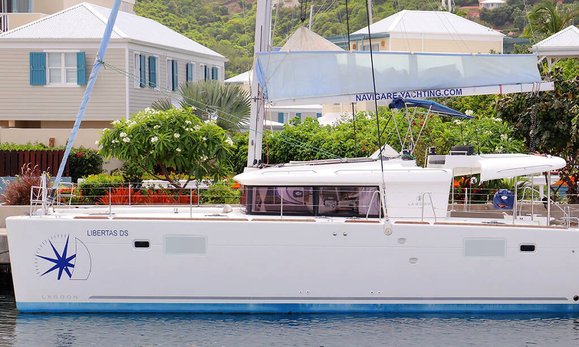 A white yacht docked at a marina with a website banner overhead.