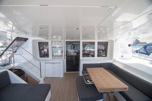 L’intérieur d’un bateau comprend un espace repas, des sièges et des fenêtres donnant sur le port de plaisance.