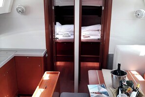 Ein kleines Zimmer mit zwei Betten, einer kleinen Küchenzeile und einem Tisch mit einer Flasche und Snacks.