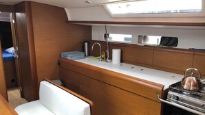 A compact galley with a sink, stove, and a small seating area. - Sun-Kissed Sailing Adventure in the Saronic Islands (Elliniko)