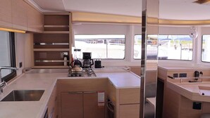 Cocina compacta con lavamanos, estufa y cafetera, con ventanas amplias que ofrecen vistas al exterior.