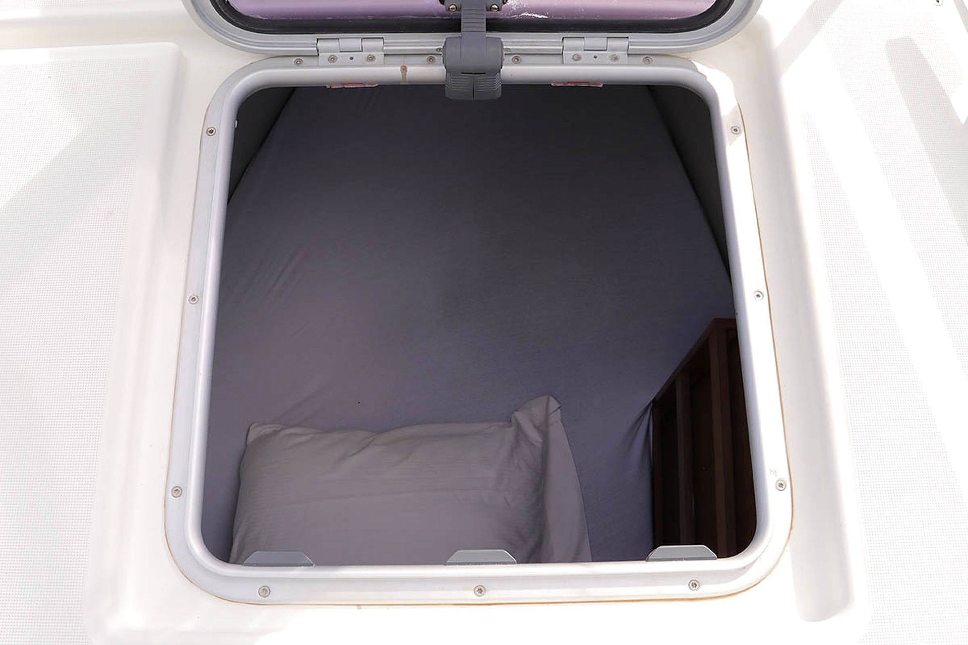 A window with a closed blind and a cushion inside.