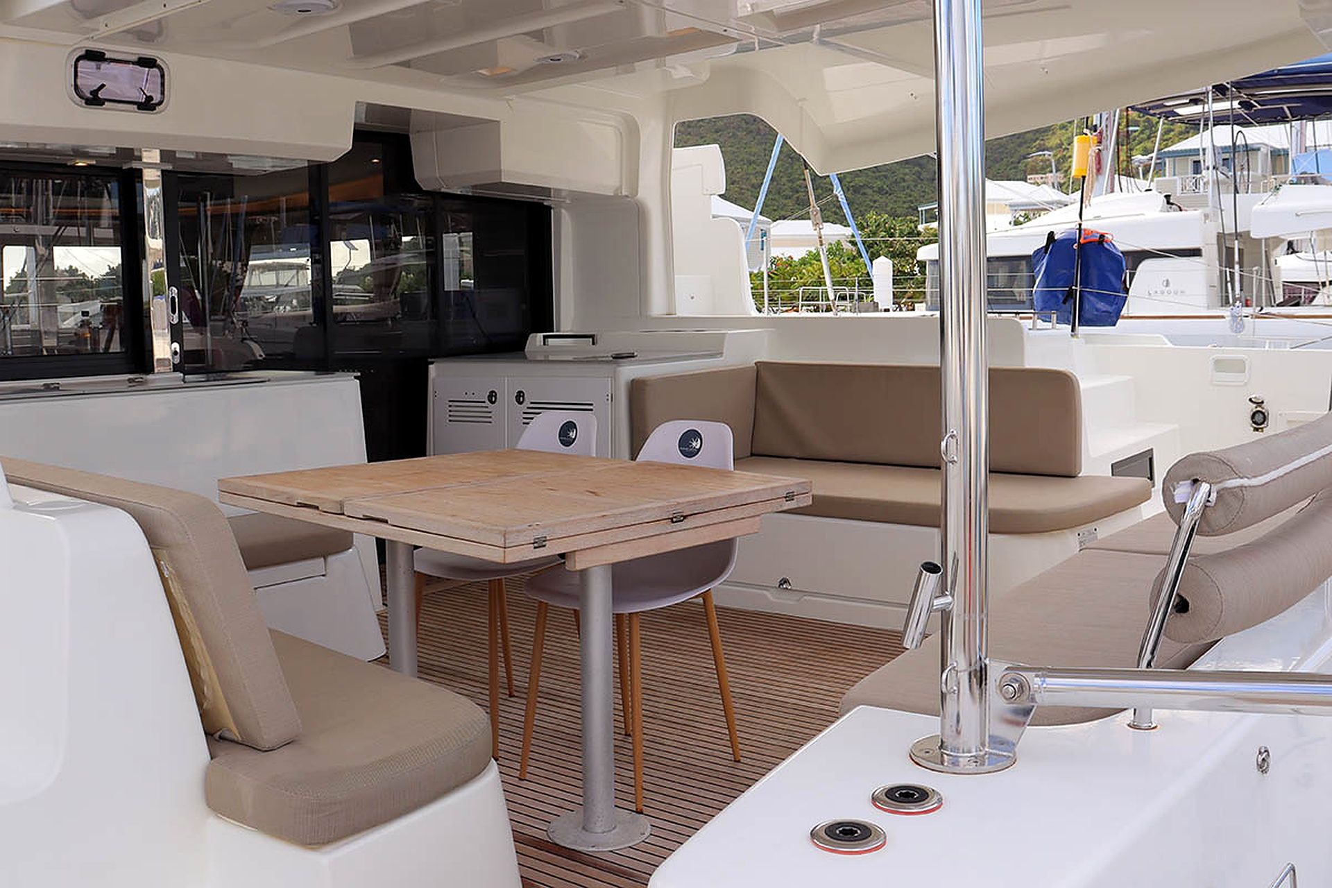 A boat's interior with a seating area, a table, and a small kitchenette.