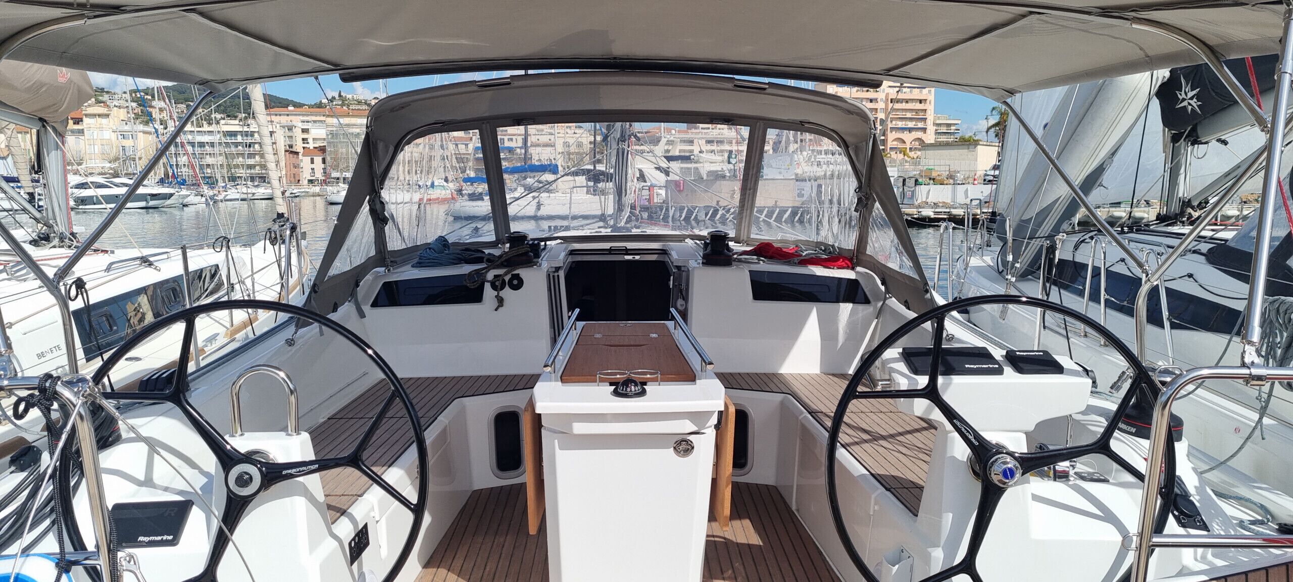 A boat's interior with a steering wheel, control panel, and wooden deck.