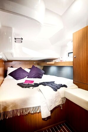 A compact cabin with a bed, a small shelf, and a wardrobe. - Sun-Kissed Sailing Adventure in Islas Esporadas (Skiathos)