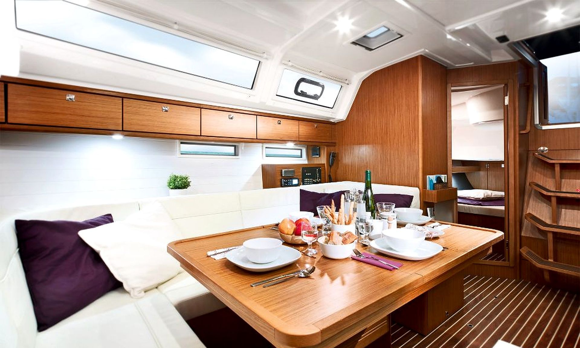 Un intérieur compact et bien éclairé, comprenant un coin repas, une petite kitchenette et un espace salon avec un banc rembourré.