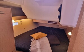 A compact sleeping area with a bed, pillows, and a headboard. - Sun-Kissed Sailing Adventure in Provence-Alpes-Côte d'Azur (Vallauris)