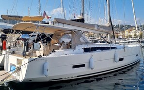 A yacht docked at a marina with multiple masts and sails, a cabin with a name 'DUFOUR', and a cityscape in the background. - Sun-Kissed Sailing Adventure in Provence-Alpes-Côte d'Azur (Vallauris)