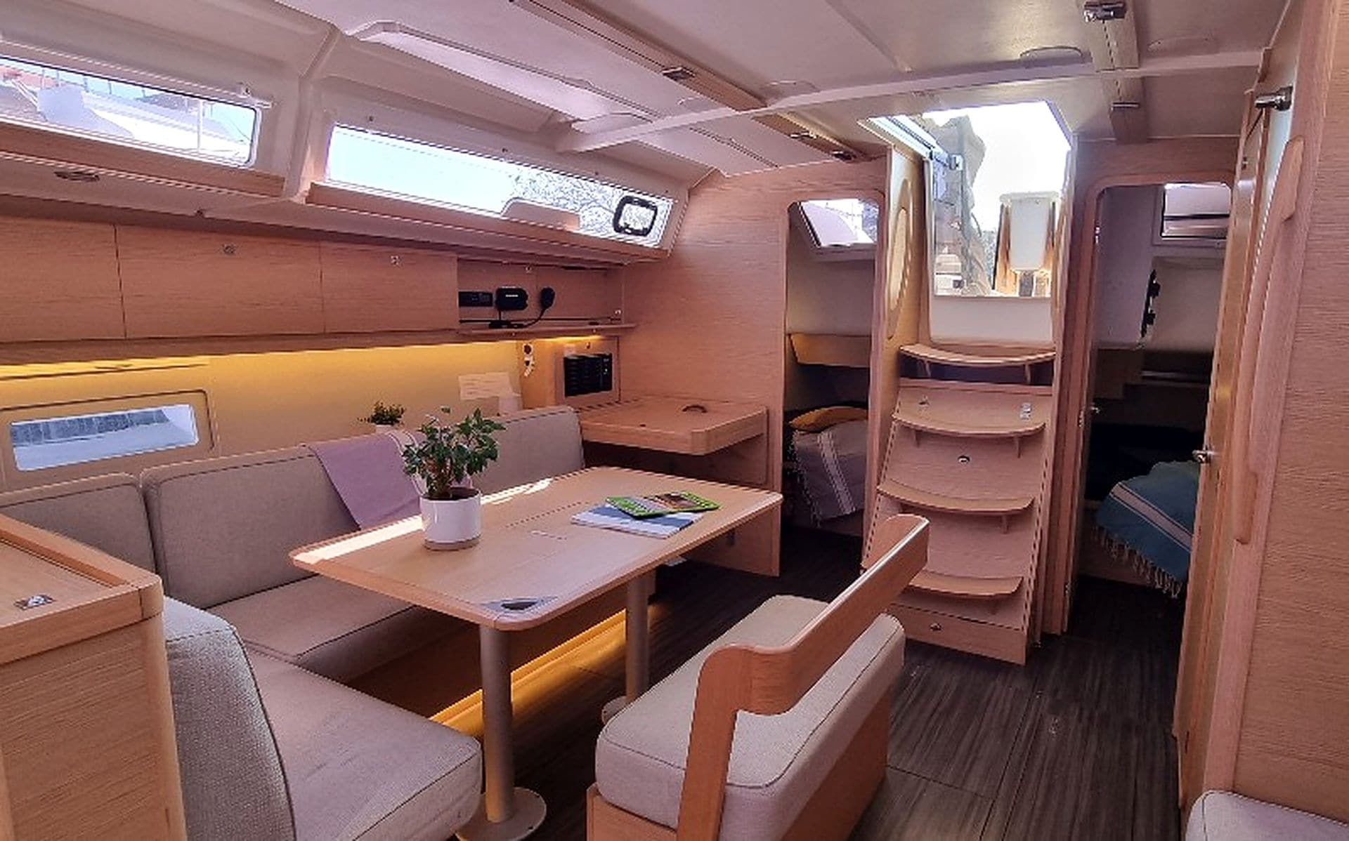 A compact interior with a dining area, seating, a small table with a plant, and a television.