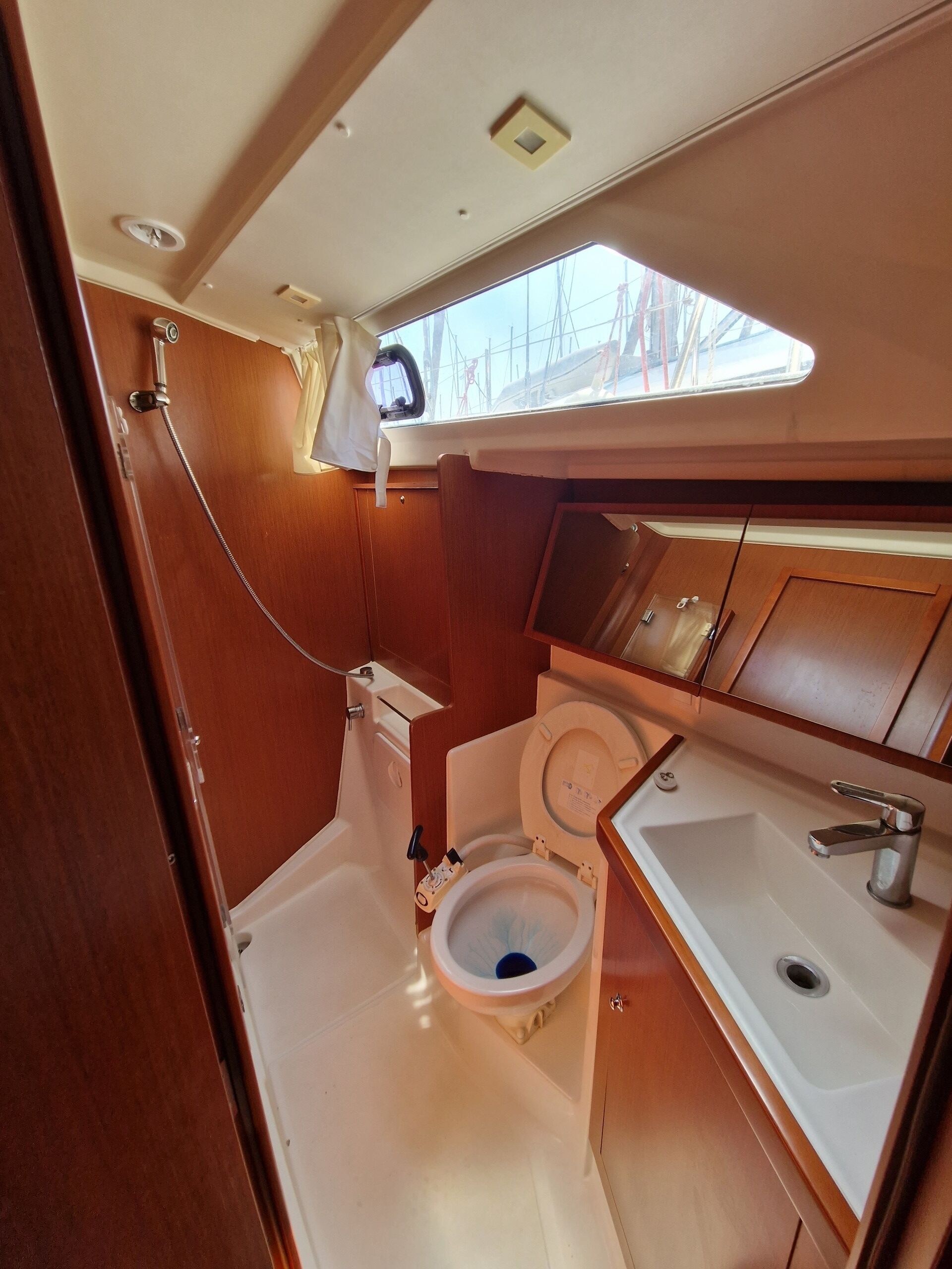 A compact bathroom with a skylight, a toilet, a sink, and a shower.