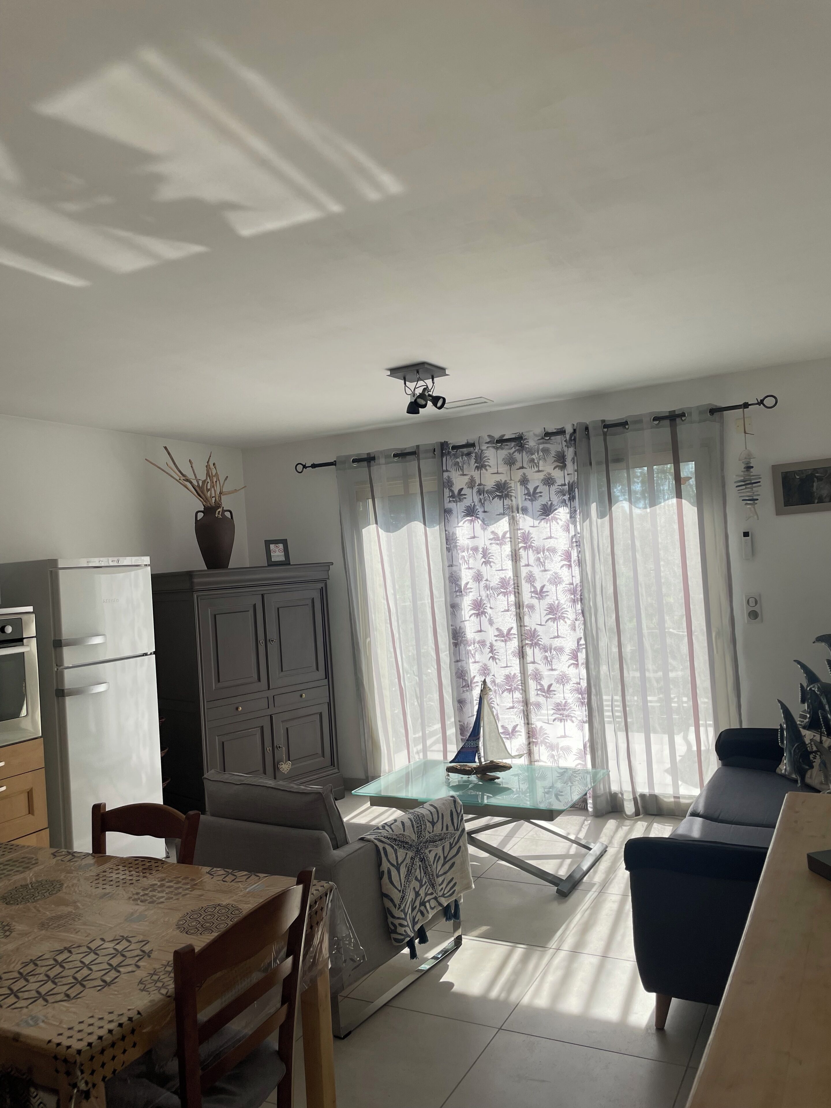 Una sala de estar con comedor, cocina y vistas a través de cortinas traslúcidas.