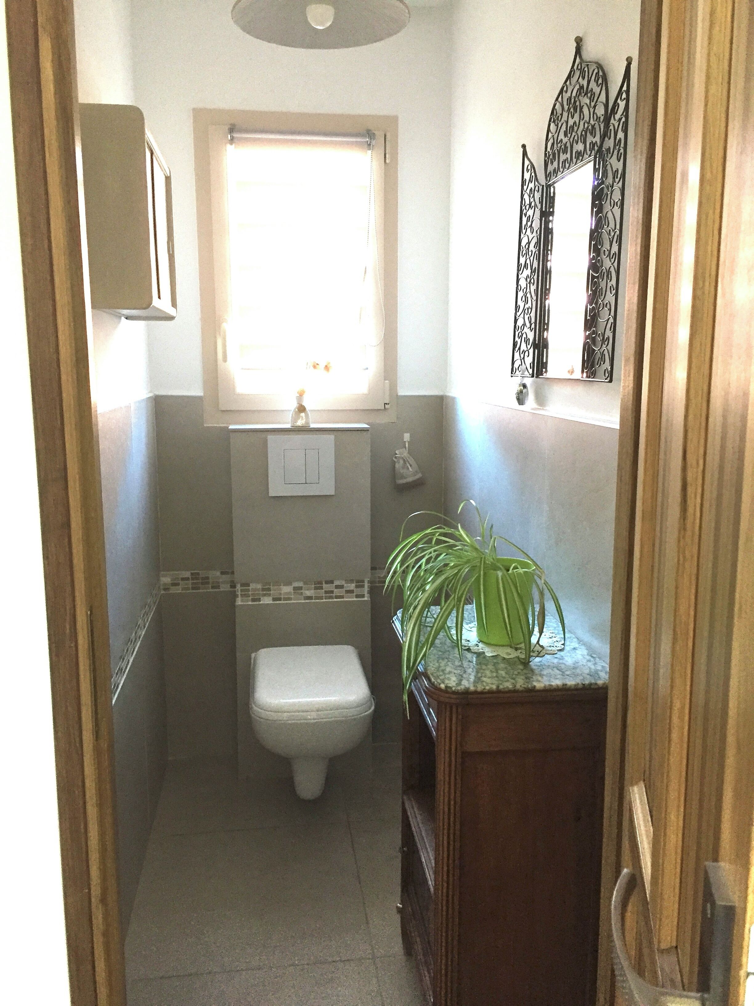 A small bathroom with a toilet, a sink, and a window.