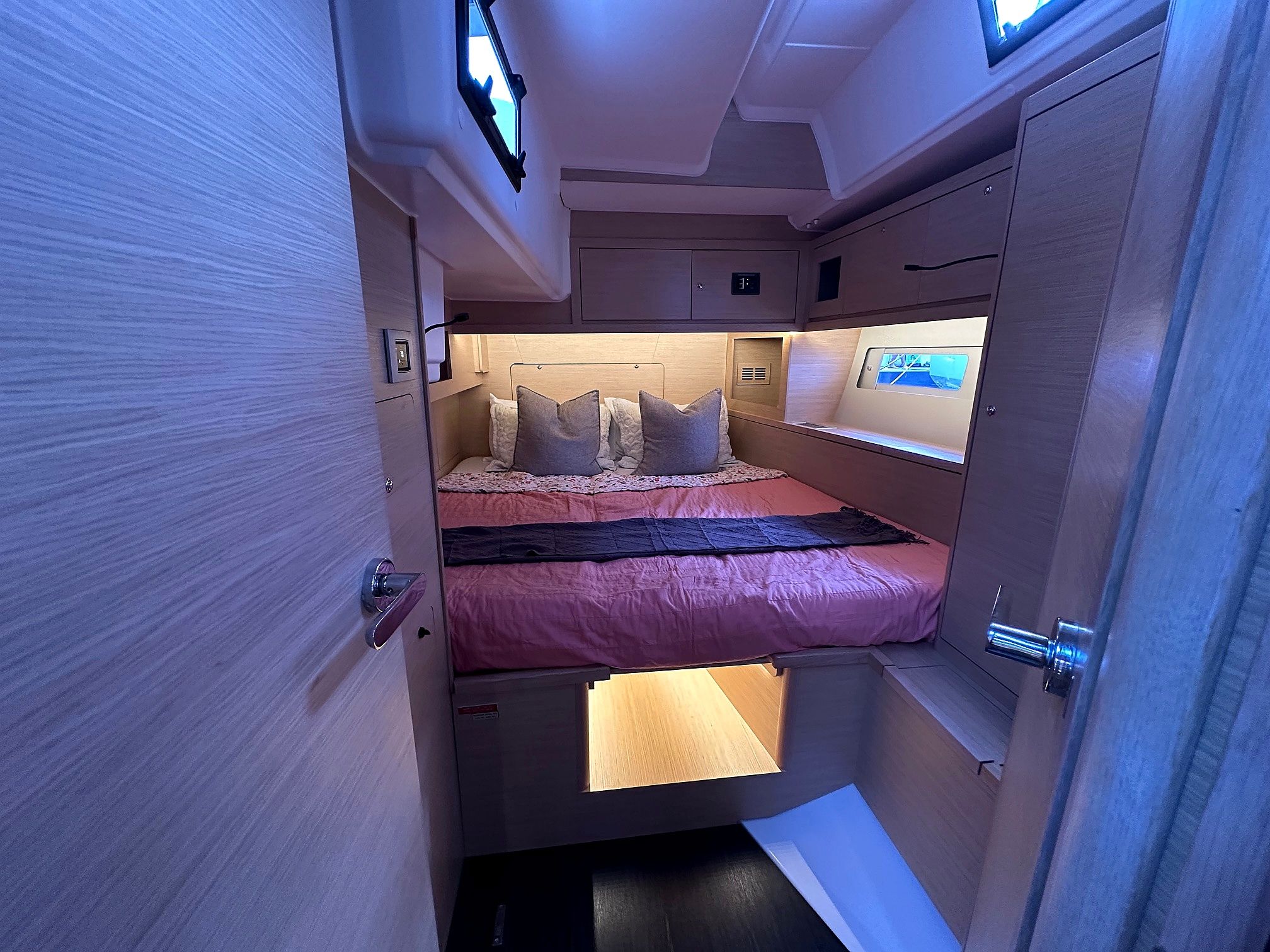 A compact, well-lit interior with a bunk bed, a small bedside table, and a control panel.