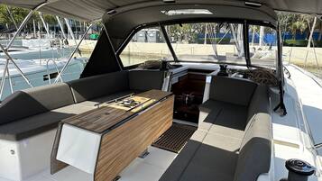 A boat's interior with a central table, cushioned seating, and a canopy overhead.
