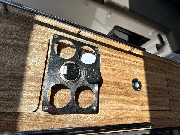 A close-up of a wooden panel with a black metal plate featuring circular cutouts and a central knob.