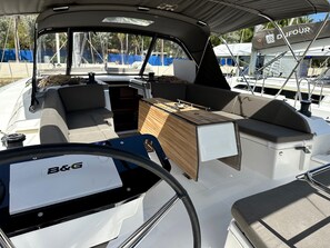 A boat's interior with a steering wheel, a B&G navigation system, and a central console with seating.