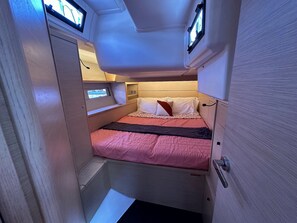 A compact, well-lit cabin with a single bed, a small window, and a door.
