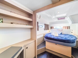 A compact bedroom with a bed, built-in shelves, a small desk, and a window with curtains. - Caribbean Dream: Sun-soaked Sailing Adventure from Tortola, Islas Vírgenes Británicas (Road Town)