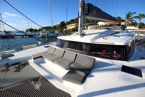 A yacht with a covered deck area, seating, and a view of the marina.