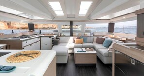 Ein modernes Interieur mit einer Küche, einer Sitzecke und großen Fenstern mit Meerblick.